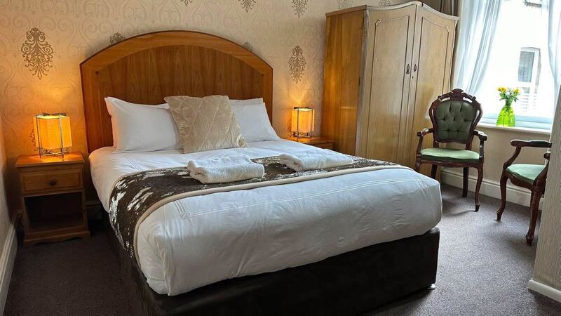 A double en-suite room with a wooden headboard, warm bedside lamps and fresh towels.