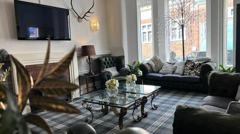 The guest lounge with green Chesterfield seating, a glass coffee table and tartan carpet.